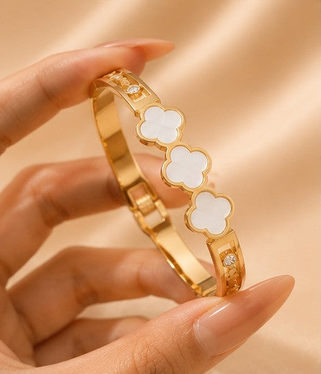 White clover gold bangle held in hand